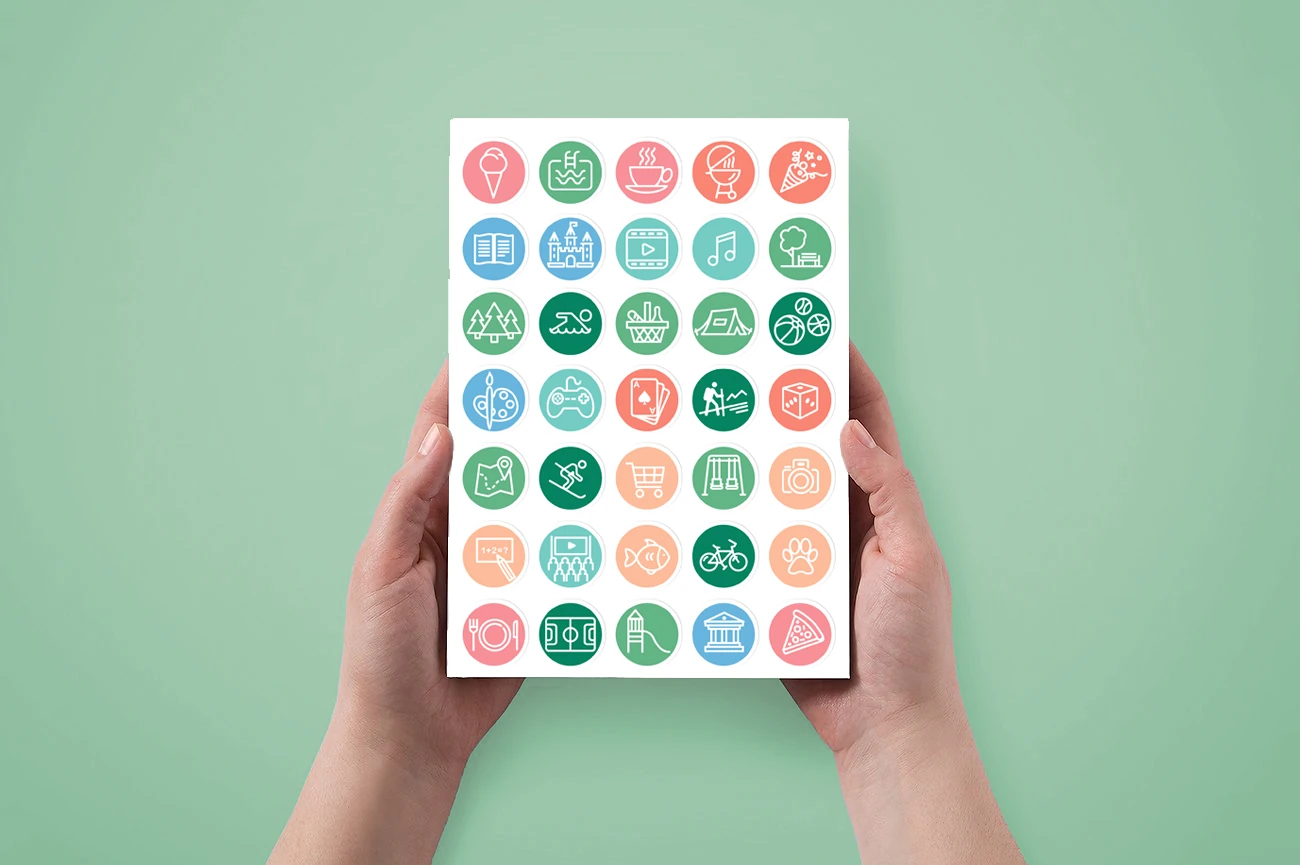A hand holding Planko's colourful activity sticker sheet.